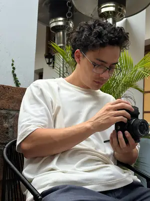 Sentado revisando la cámara, polera blanca UEBOS