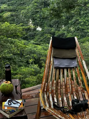 Una polera negra UEBOS sobre una silla de madera frente a las montañas