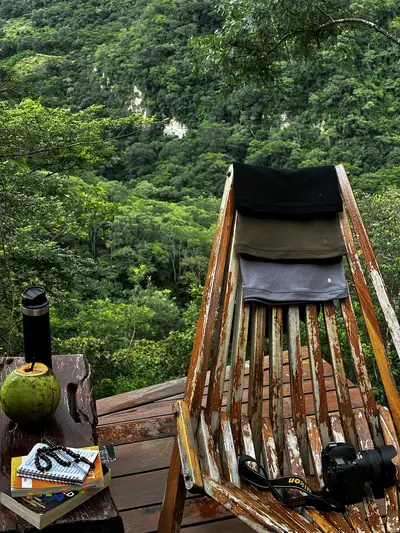 Una polera negra UEBOS sobre una silla de madera frente a las montañas